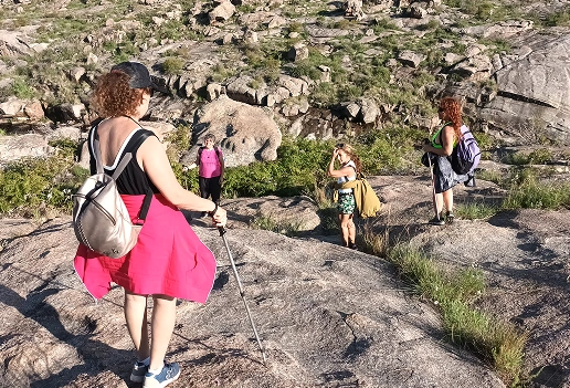 Grupo de personas haciendo senderismo en un terreno rocoso y montañoso con vegetación escasa.