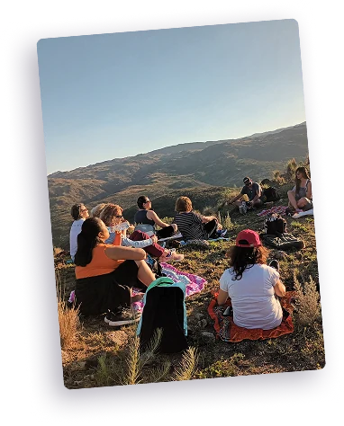 Personas sentadas en una colina al atardecer, contemplando el paisaje.